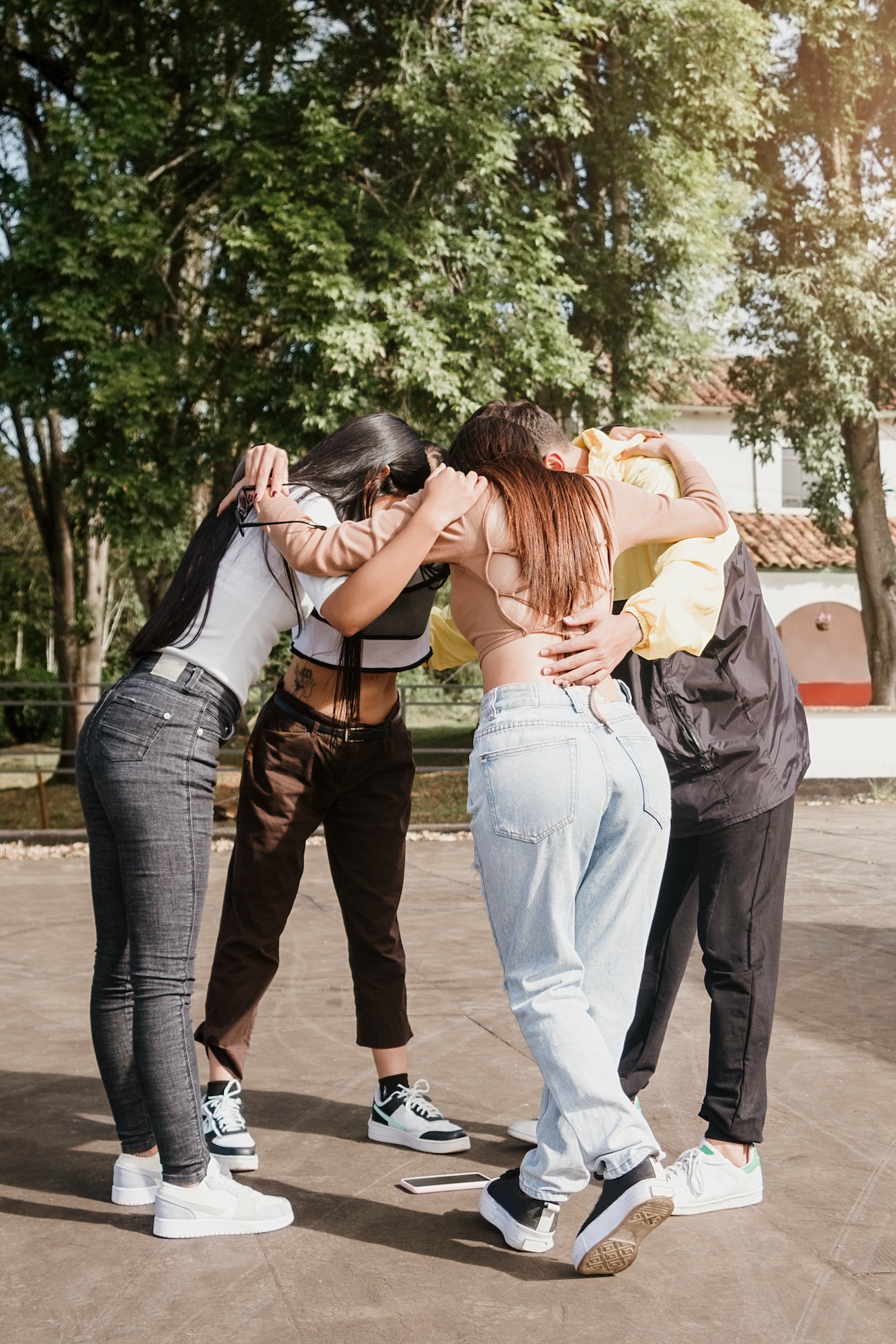 Group of friends hugging each other taking a selfie from the ground with their cell phone