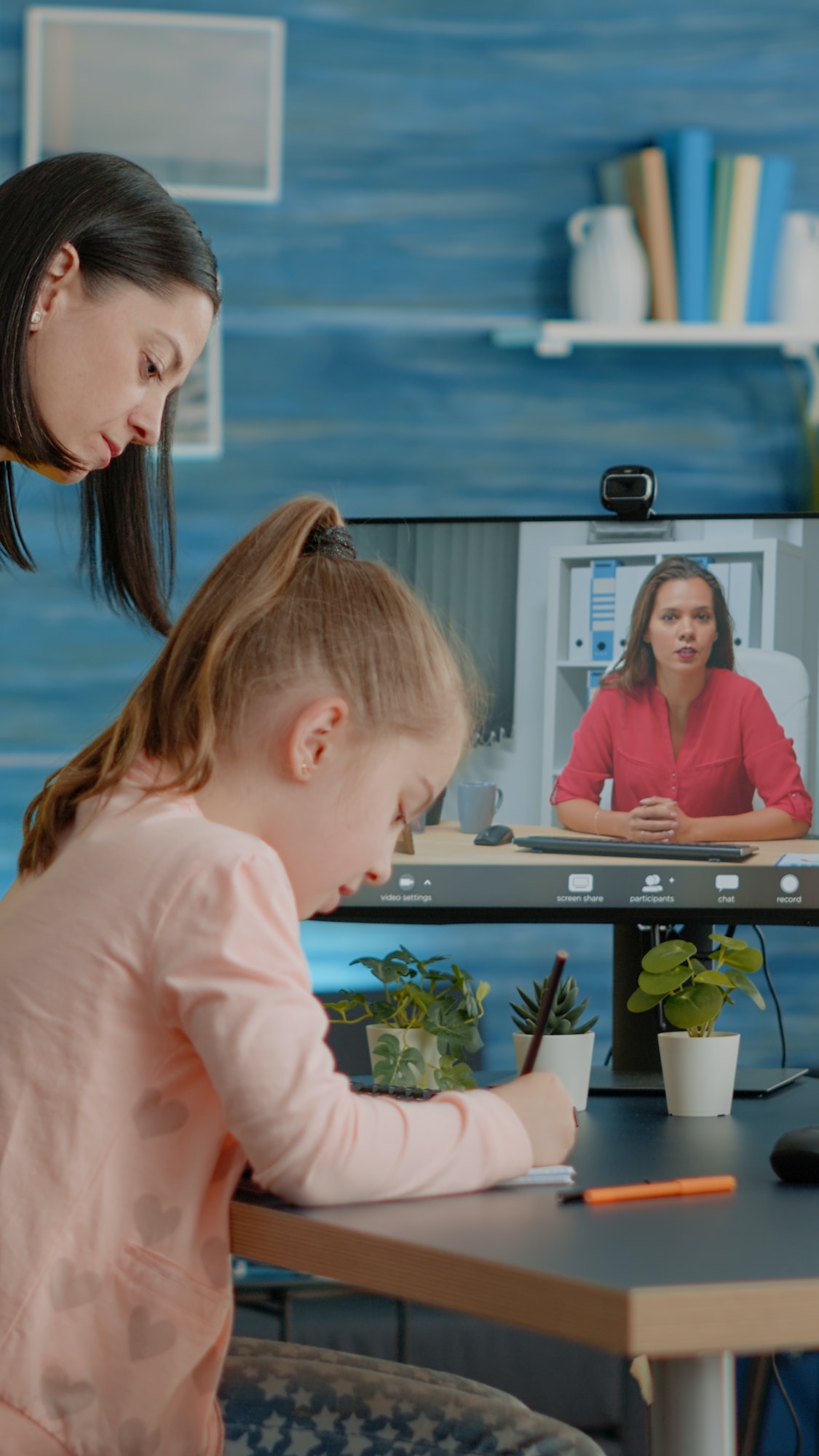 Pupil taking notes on textbook using video call with teacher